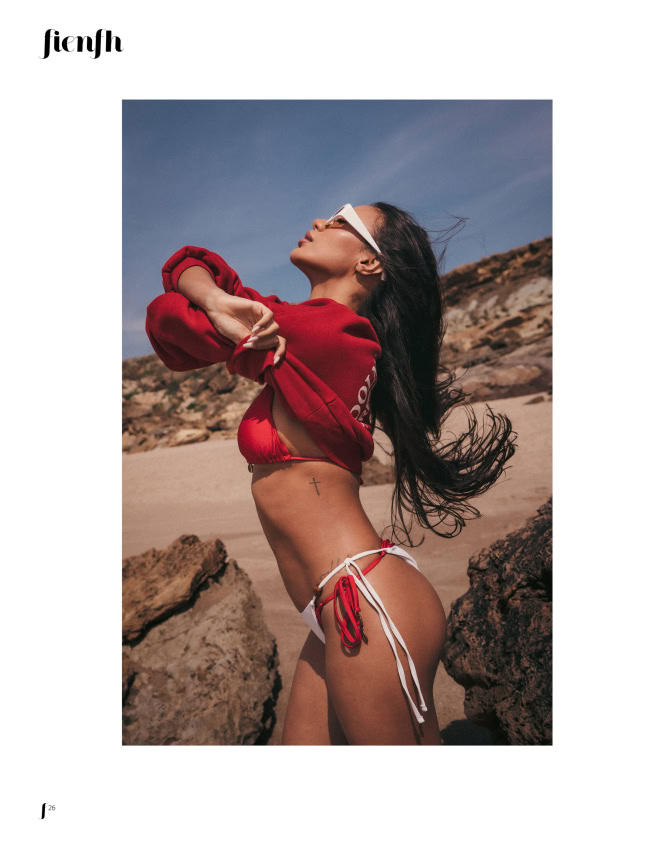Magazine editorial page showing a woman in a red top and white bikini on a rocky beach