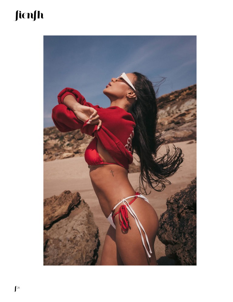 Magazine editorial page showing a woman in a red top and white bikini on a rocky beach